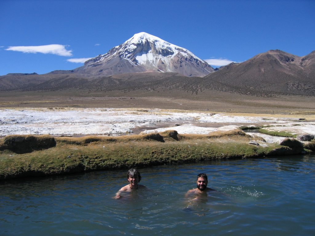Ballester y Trino bañándose en las Aguas Termales Colchapata en la Comunidad Jila Uta Manasaya, con el Sajama al fondo